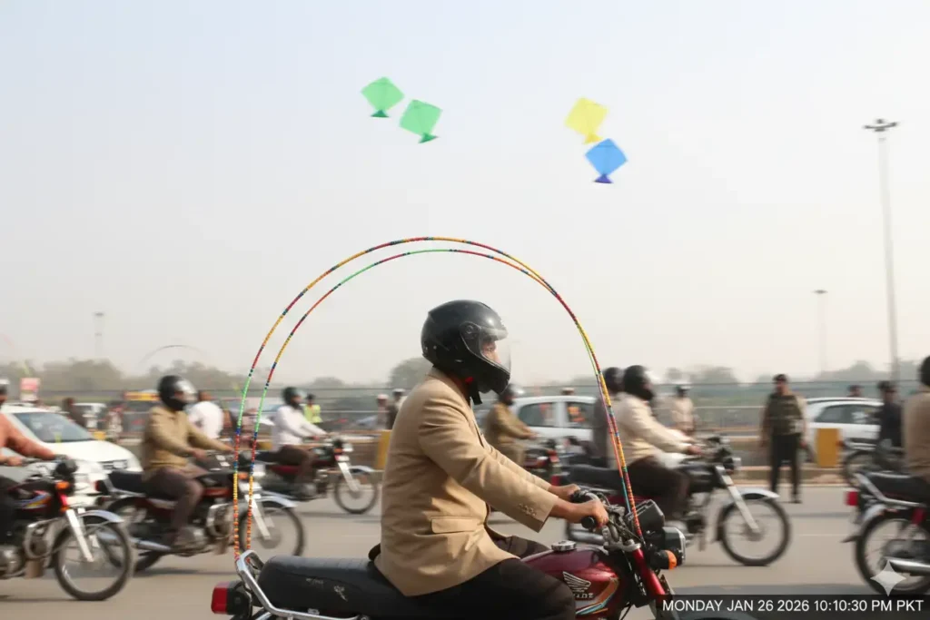 Motorcycle rider using U-shaped safety rod while riding during Basant celebrations in Lahore.